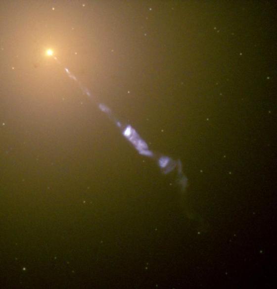 Streaming out from the center of the galaxy M87 like a cosmic searchlight is one of nature's most amazing phenomena, a black-hole-powered jet of electrons and other sub-atomic particles traveling at nearly the speed of light. In this NASA Hubble Space Telescope image, the blue of the jet contrasts with the yellow glow from the combined light of billions of unseen stars and the yellow, point-like globular clusters that make up this galaxy. Photo Credit: NASA