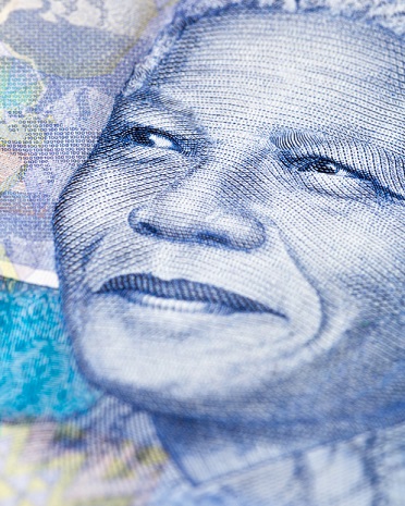 Extreme close-up of a detail of a new South African Hundred Rand banknote, featuring an engraving of the face of iconic statesman Nelson Mandela, giving his trademark smile. South African wildlife and African designs form the watermarked background. Photo: Istockphoto> Copyright.