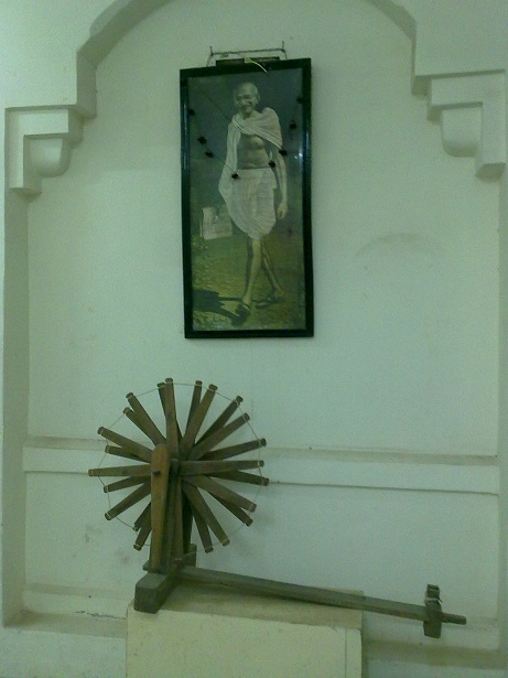 A replica of Nazarali Bapa's spinning wheel below Mahatma Gandhi's portrait at the Amreli Museum. The original wheel was designed to honour Gandhi's visit to Saurashtra. Photo: Khushid Makani Collection. 