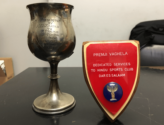 Mr. Premji Vaghela was awarded the cup on the left for scoring 150 runs in a cricket match. The plaque on the right was given to him for his contribution to the Hindu Sports Club. Photo: Premji Vaghela Family Collection. Copyright. 