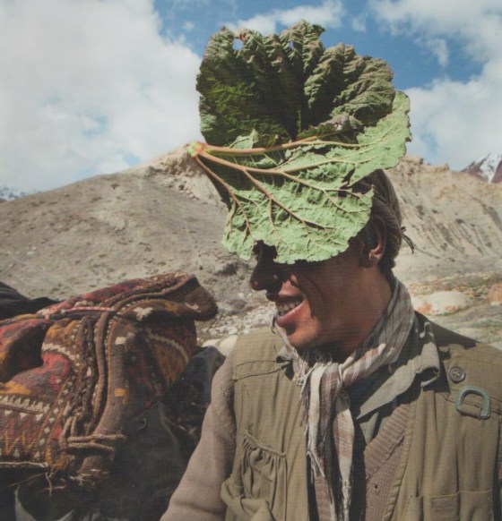 Using a wild rhubarb leaf as his parasol, a traveller shields his face against the strong sun of the high Pamir Mountains in Afghanistan. Photo/Caption: With Our Own Hands