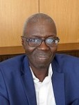 Portrait of Professor Souleymane Bachir Diagne, a Senegalese philosopher, smiling while wearing glasses and a blue blazer.
