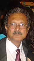 Author Zahir K. Dhalla, a middle-aged man with glasses and curly hair, wearing a suit and tie, is pictured against a blurred background.