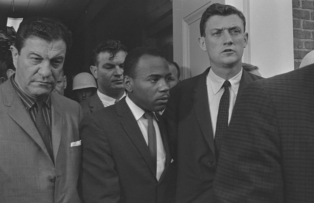 Photograph shows James Meredith walking on the campus of the University of Mississippi, accompanied by U.S. marshals. LOC photo reproduced in Simerg