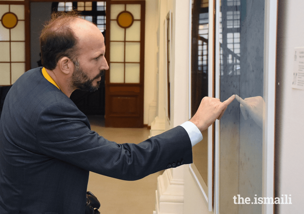 A man examining an art piece in an exhibition hall, reflecting thoughtful engagement.